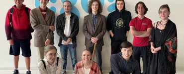 Photo of 10 high school students standing in front of a white wall with a large C89.5 logo.