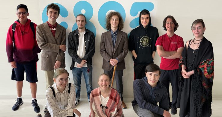 Photo of 10 high school students standing in front of a white wall with a large C89.5 logo.