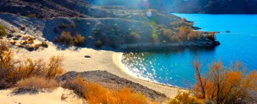 Picture of a beach on a desert lake with mountains in the background during sunset.