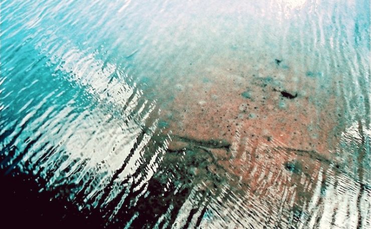 Blue water with a transparent spot showing the bottom of the water body.