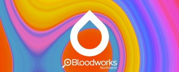 A rainbow-colored swirly background with white outline of a raindrop. Inside the raindrop is a QR code, linking, to bloodworksnw.org