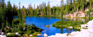 A clear blue lake surrounded by trees and rocks.