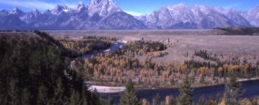 An autumn landscape with mountains and a winding river.