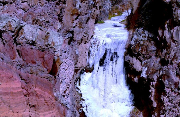 A mountain waterfall with a steep drop, fully frozen.