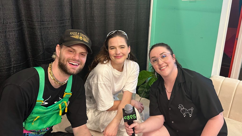 An image of Tukker and Sofi of the band Sofi Tukker sitting on a white sofa with Harmony Soleil