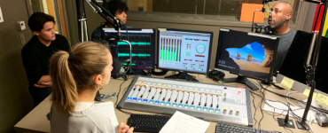 Three students in the c895 studios recording a podcast episode with an adult host
