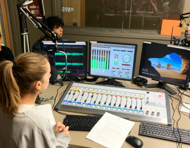 Three students in the c895 studios recording a podcast episode with an adult host