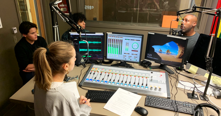 Three students in the c895 studios recording a podcast episode with an adult host