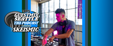 DJ Skeismic performing at a mixer table during a live session for the C89.5 Guestmix Seattle podcast in a room with large windows.