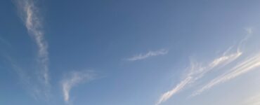 Wispy white clouds scattered across a bright blue sky on a sunny day.