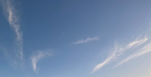 Wispy white clouds scattered across a bright blue sky on a sunny day.