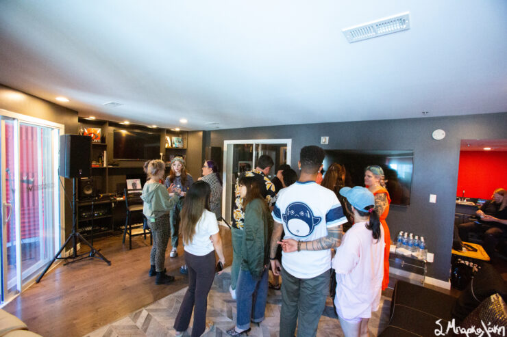 Group of people engaging in a lively conversation at an indoor gathering, one person wearing a shirt.