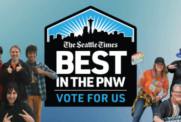 Group of people smiling and posing playfully with props, encouraging votes for 'The Seattle Times' as 'Best in the PNW'. Prominent blue logo in the center with text.