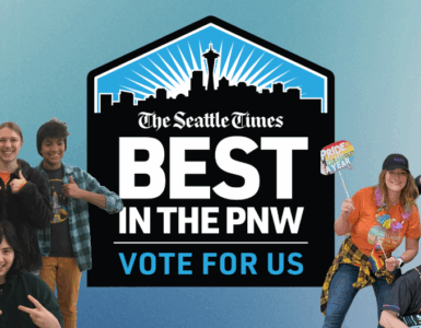 Group of people smiling and posing playfully with props, encouraging votes for 'The Seattle Times' as 'Best in the PNW'. Prominent blue logo in the center with text.