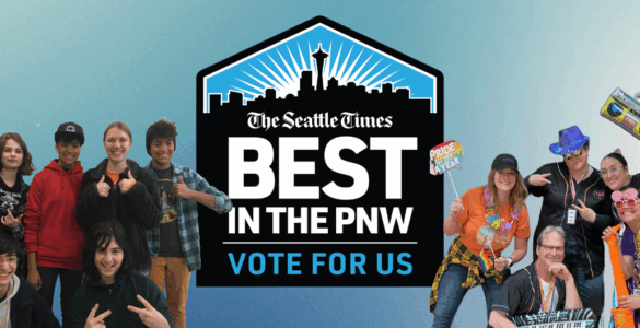 Group of people smiling and posing playfully with props, encouraging votes for 'The Seattle Times' as 'Best in the PNW'. Prominent blue logo in the center with text.