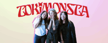 Three individuals posing with smiles in front of a neon sign that reads "TOKiMONSTA.