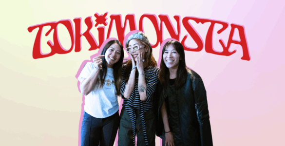 Three individuals posing with smiles in front of a neon sign that reads "TOKiMONSTA.