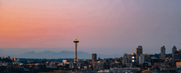 Panoramic view of Seattle skyline at sunset with the Space Needle prominently featured.