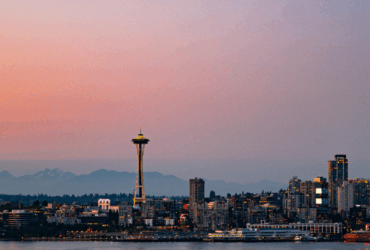 Panoramic view of Seattle skyline at sunset with the Space Needle prominently featured.