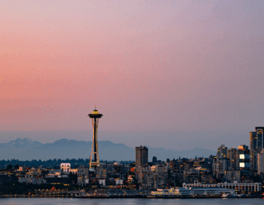 Panoramic view of Seattle skyline at sunset with the Space Needle prominently featured.