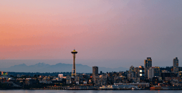 Panoramic view of Seattle skyline at sunset with the Space Needle prominently featured.