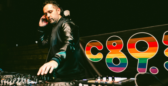 DJ performing at a mixing console with a colorful "c895" logo in the background.