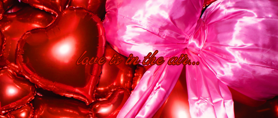 An array of shiny red heart-shaped balloons with a prominent pink bow, featuring the phrase "love is in the air..." floating amidst them.