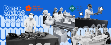 A group of individuals engaged in food distribution activities are depicted. They are handling packages and various items, with tables set up for organization. The scene includes logos for Ballard Food Bank and Puget Sound Energy against a background of stylized zeros.