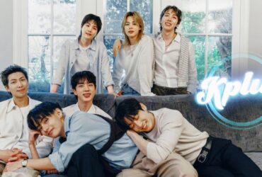 A group of six people smiling and sitting on a couch in a cozy, light-filled room with large windows. The word "Kplus" is displayed in the corner of the image.
