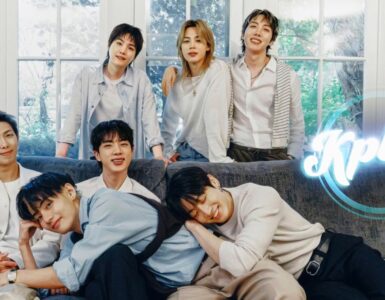 A group of six people smiling and sitting on a couch in a cozy, light-filled room with large windows. The word "Kplus" is displayed in the corner of the image.